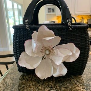 Black wicker purse w/beautiful flower. Approximately 10”x10” in good condition.